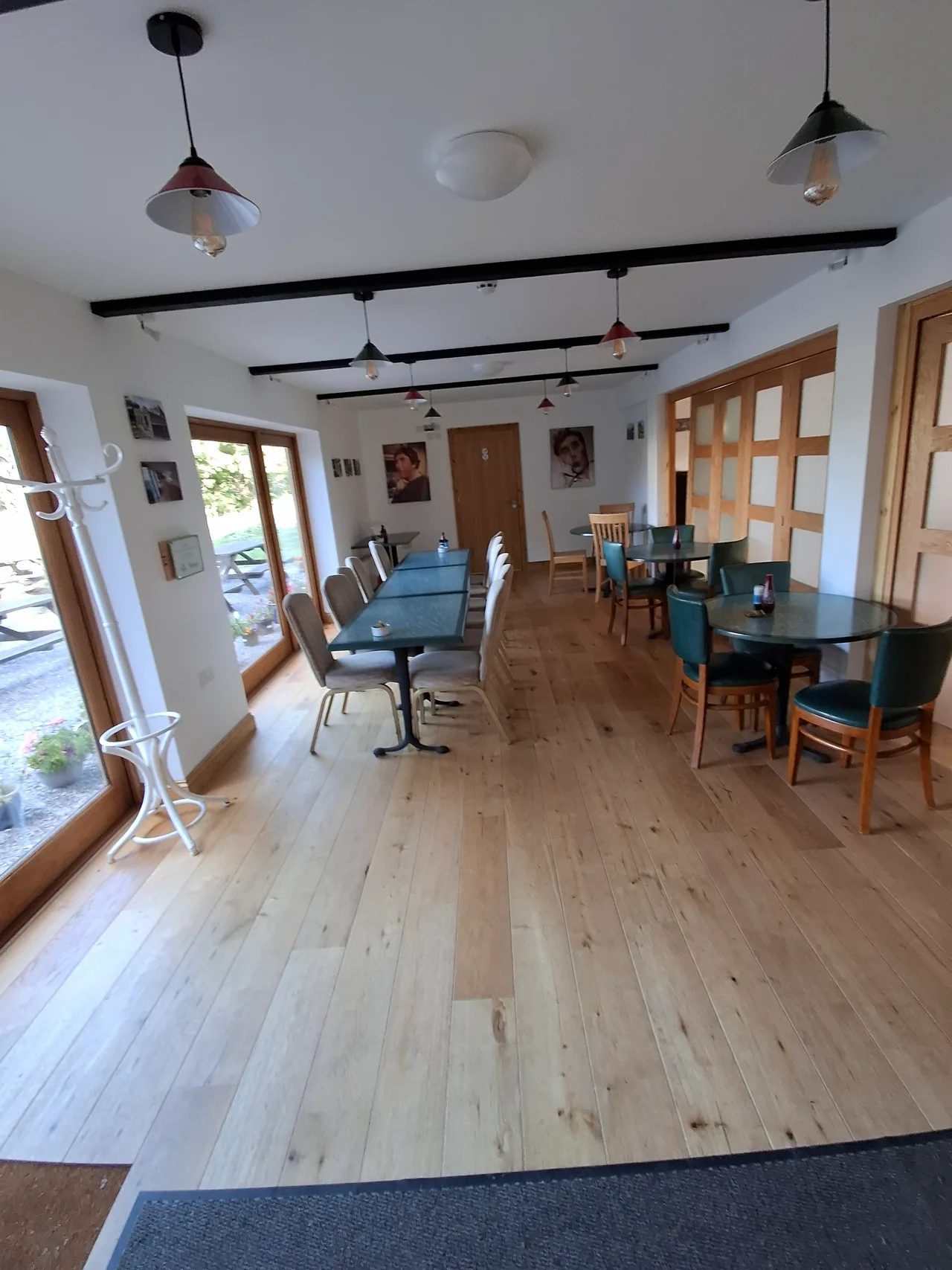Additional café tables beside courtyard windows and folding wooden partitions in the Dame June Whitfield Centre